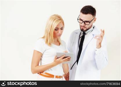 Male doctor and female patient looks at tablet computer for health data record. Healthcare and medical service.