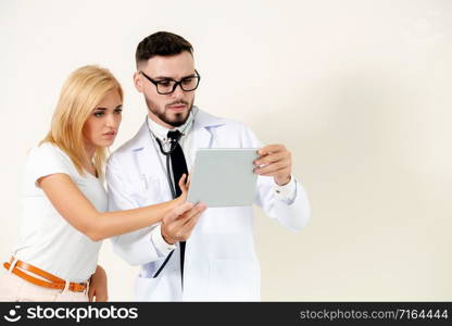 Male doctor and female patient looks at tablet computer for health data record. Healthcare and medical service.. Male Doctor and Female Patient in Hospital.