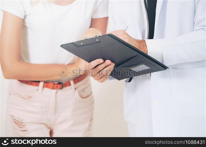 Male doctor and female patient with documents of patients health record are having conversation in hospital. Healthcare and medical service.