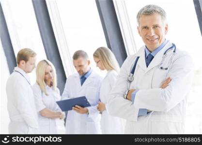 Male doctor and her team. Successful mature male doctor and his team on background in clinical office