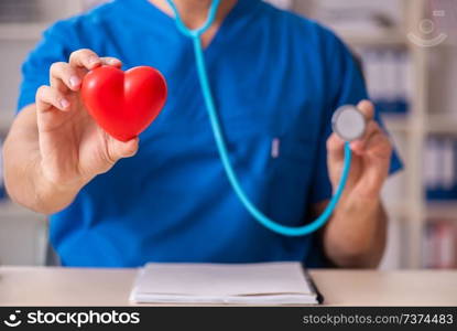 Male doctor cardiologist holding heart model 