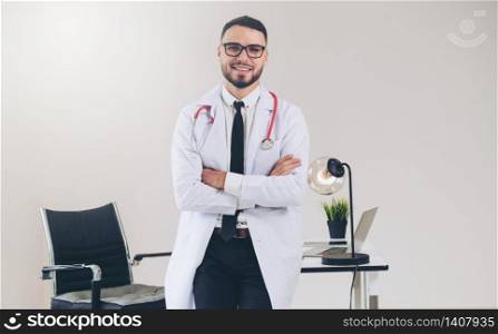 Male doctor crossed arms standing at office table in the hospital. Medical and healthcare concept.. Male doctor crossed arms standing in the hospital.