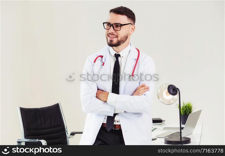 Male doctor crossed arms standing at office table in the hospital. Medical and healthcare concept.