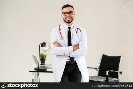 Male doctor crossed arms standing at office table in the hospital. Medical and healthcare concept.. Male doctor crossed arms standing in the hospital.