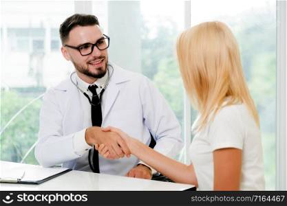 Male doctor doing handshake with female patient in hospital office. Healthcare and medical service.. Male Doctor and Female Patient in Hospital Office