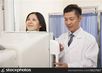 Male Doctor Examining Female Patient&rsquo;s Mid Section With X-ray Machine
