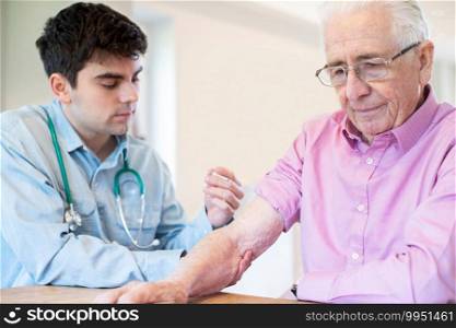 Male Doctor Giving Senior Man Vaccine Injection In Arm With Syringe