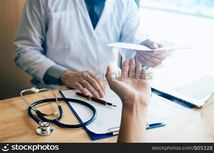 Male doctor handing a prescription to the patient.