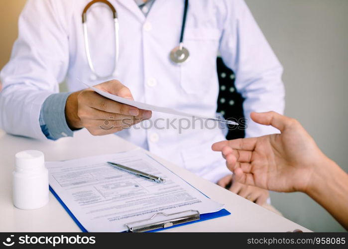 Male doctor handing a prescription to the patient.