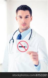 male doctor holding no smoking sign in hands. male doctor holding no smoking sign