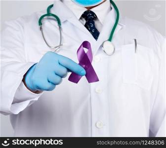 male doctor in a white coat and tie stands and holds a purple silk ribbon in the form of a loop, wearing blue sterile medical gloves. Symbol of early research and disease control, Alzheimer&rsquo;s disease