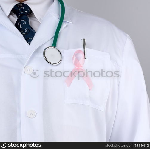 male doctor in a white coat and tie stands and holds a pink silk ribbon in the form of a loop, symbol of the fight against breast cancer in October