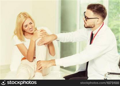 Male doctor is examining female patient in hospital ward. Healthcare and medical service.