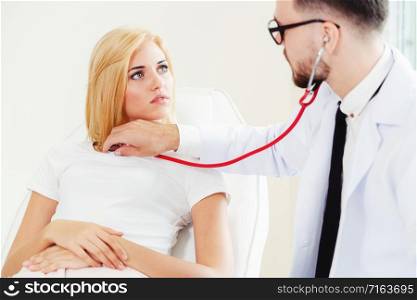 Male doctor is talking and examining female patient in hospital office. Healthcare and medical service.