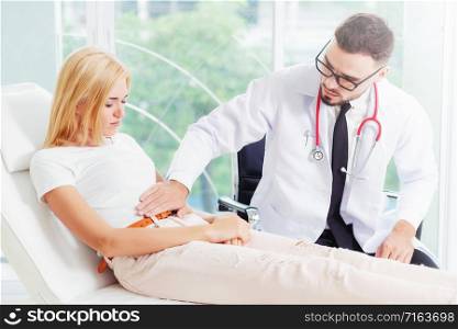 Male doctor is talking and examining female patient in hospital office. Healthcare and medical service.