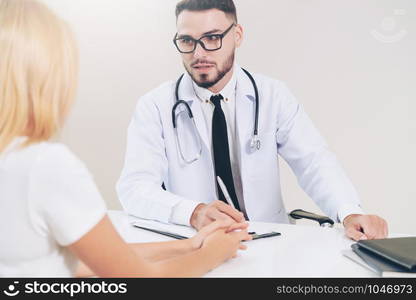 Male doctor is talking to female patient in hospital office. Healthcare and medical service.