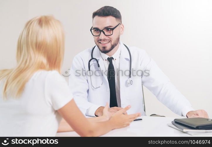 Male doctor is talking to female patient in hospital office. Healthcare and medical service.