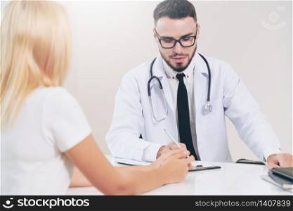 Male doctor is talking to female patient in hospital office. Healthcare and medical service.. Male Doctor and Female Patient in Hospital Office