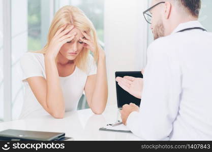 Male doctor is talking to serious female patient in hospital office. Healthcare and medical service.. Male Doctor and Female Patient in Hospital Office