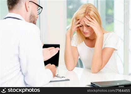Male doctor is talking to serious female patient in hospital office. Healthcare and medical service.. Male Doctor and Female Patient in Hospital Office
