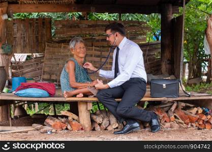 Male Doctor listening heartbeat and breathing of Elderly Woman with Stethoscope with First Aid Medical Box.