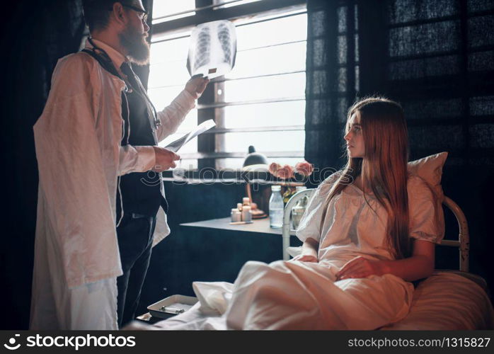 Male doctor looking at x-ray picture of sick woman in hospital. Sickness of female patient in clinic, health recovery and treatment. Male doctor looking at x-ray picture of sick woman