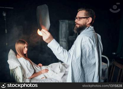 Male doctor looking at x-ray picture of sick woman in hospital. Sickness of female patient in clinic, health recovery and treatment. Male doctor looking at x-ray picture of sick woman