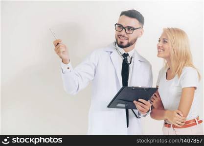 Male doctor points pen at empty copy space while standing beside female patient.. Male doctor with patient points pen at copy space.