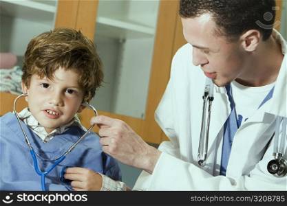 Male doctor putting a stethoscope on the ears of a boy