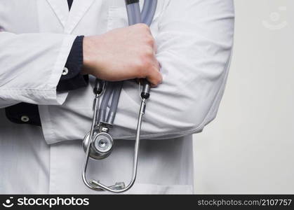 male doctor s hand holding stethoscope hand against white backdrop