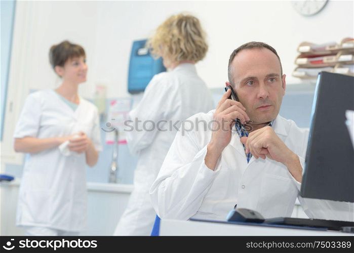male doctor sitting at her office while calling a patient