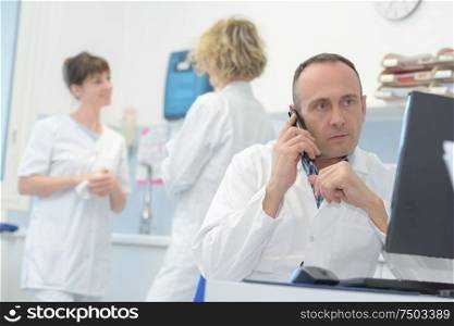 male doctor sitting at her office while calling a patient