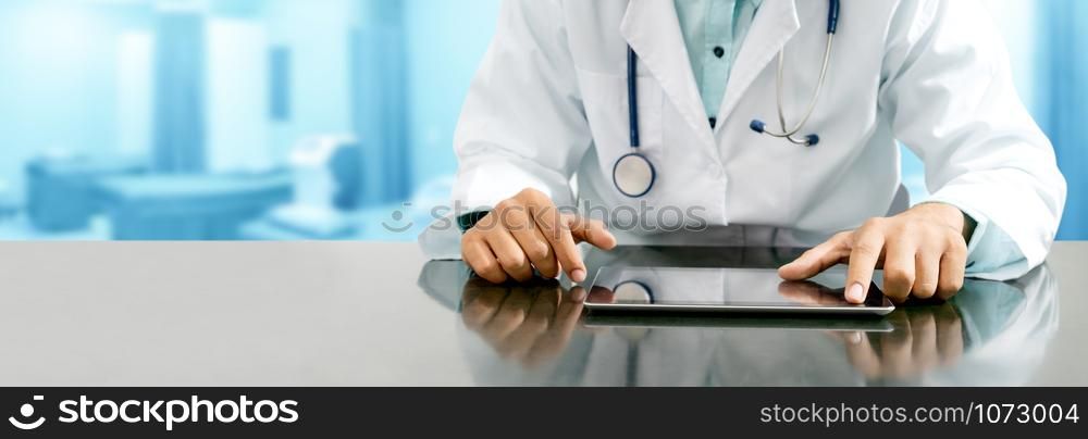 Male doctor sitting at table with tablet computer in hospital office. Medical healthcare staff and doctor service.