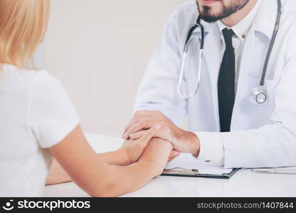 Male doctor soothes a female patient in hospital office while holding the patients hands. Healthcare and medical service.. Male Doctor and Female Patient in Hospital Office