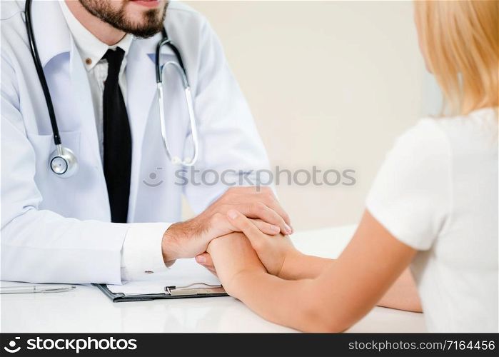 Male doctor soothes a female patient in hospital office while holding the patients hands. Healthcare and medical service.. Male Doctor and Female Patient in Hospital Office
