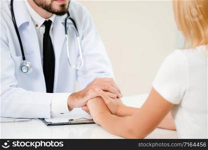 Male doctor soothes a female patient in hospital office while holding the patients hands. Healthcare and medical service.. Male Doctor and Female Patient in Hospital Office