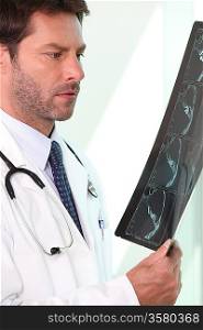 Male doctor stood holding and examining x ray