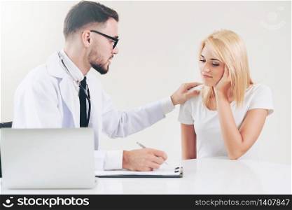 Male doctor talks to female patient in hospital office while writing on the patients health record on the table. Healthcare and medical service.. Male Doctor and Female Patient in Hospital Office