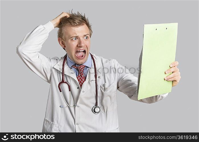 Male doctor terrified looking at medical reports over gray background