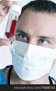 Male doctor wearing face mask with Coronavirus COVID-19 blood sample.
