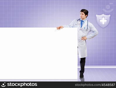 Male doctor with banner. Young male doctor leaning upon blank banner. Place for text