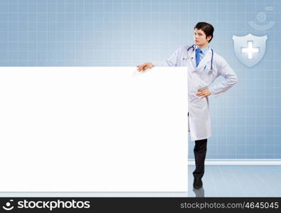 Male doctor with banner. Young male doctor leaning upon blank banner. Place for text