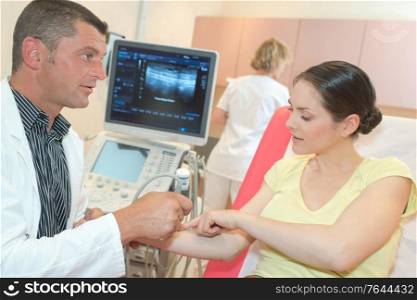 male doctor with female patient undergoing arm echography