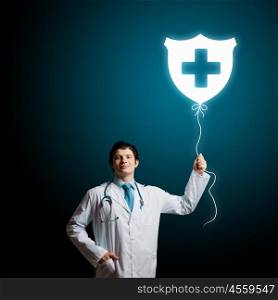 Male doctor. Young male doctor holding balloon with medical sign. Health guard