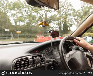 Male driver hand holding steering wheel of a car on english road