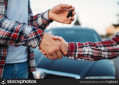 Male driving instructor gives the car keys to female student after exam, successful end of car school concept. Test for drivers, automobile course . Driving instructor gives car key to female student