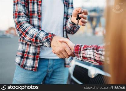 Male driving instructor gives the car keys to female student after exam, successful end of car school concept. Test for drivers, automobile course. Driving instructor gives car key to female student