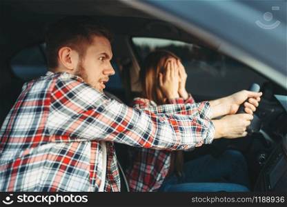 Male driving instructor helps the novice driver to avoid an accident, car school concept. Test for beginner. Driving Instructor helps driver to avoid accident