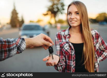 Male driving teacher gives the keys to female student after exam, successful end of car school concept. Test for drivers, automobile course. Driving teacher gives the keys to female student