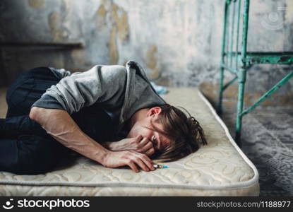 Male drug addict with syringe in hand sleeping in bed after dose. Addiction concept, narcotic addicted people. Male drug addict sleeping in bed after dose